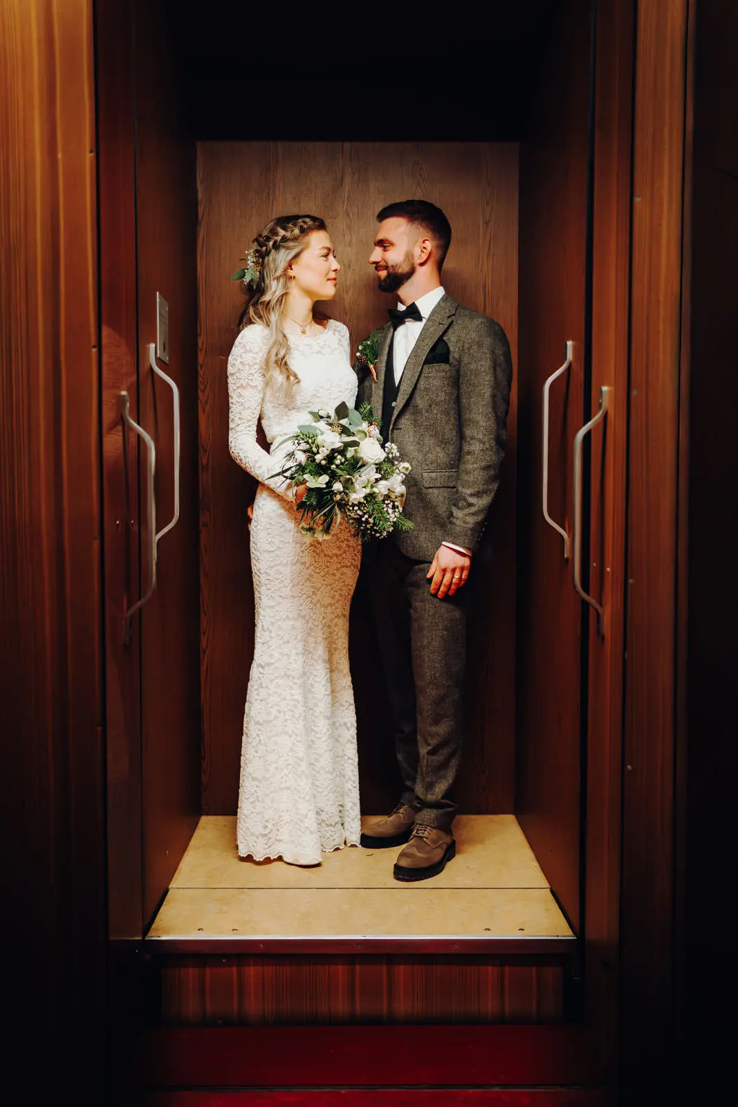 Brautpaar schaut sich an im Aufzug Rathaus Leipzig Braut und Braeutigam schauen sich zugewandt an im warmen Licht des holzverkleideten Aufzugs im Neuen Rathaus Leipzig. Hochzeit Ratsplenarsaal Leipzig