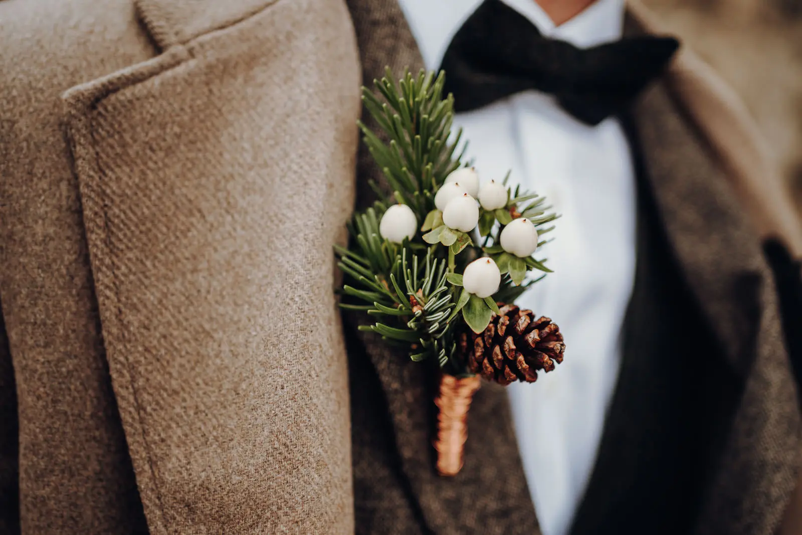 Boutonniere Braeutigam – Tannenzweig und Zapfen Winterliche Boutonniere am Revers des Braeutigams mit Tannenzweig, weissen Beeren und Tannenzapfen.