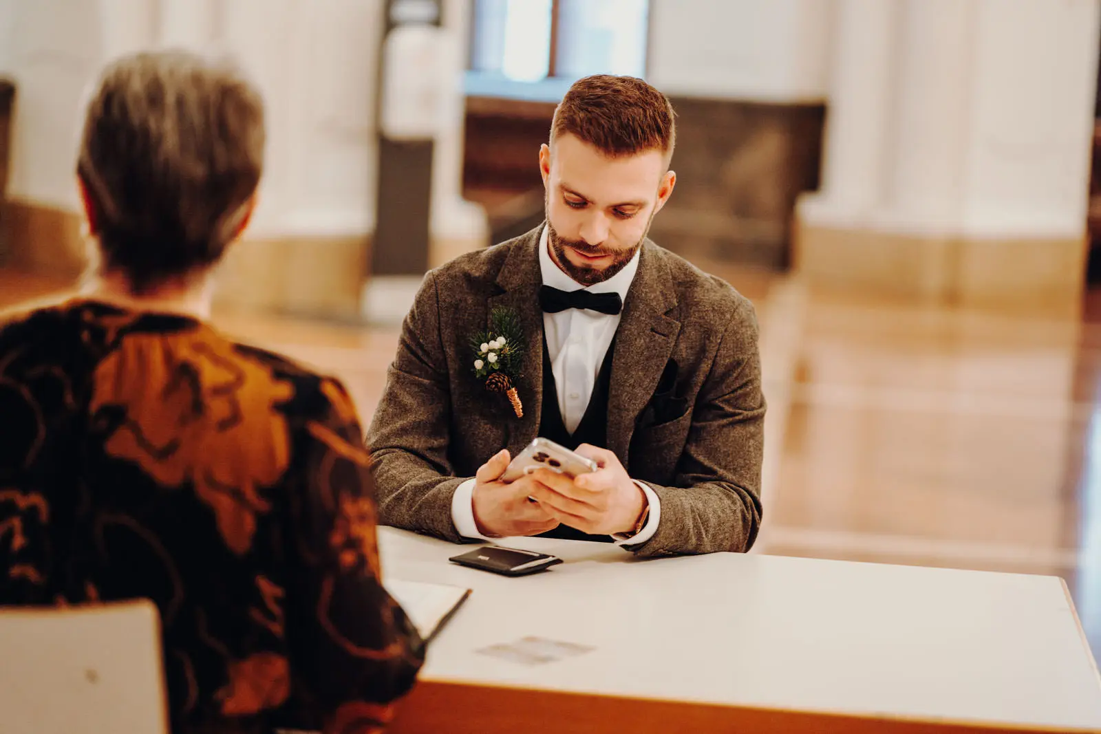 Braeutigam bei Anmeldung im Neuen Rathaus Leipzig Braeutigam im Tweed-Anzug mit Boutonniere sitzt an einem Schalter im hellen Foyer des Neuen Rathauses Leipzig.