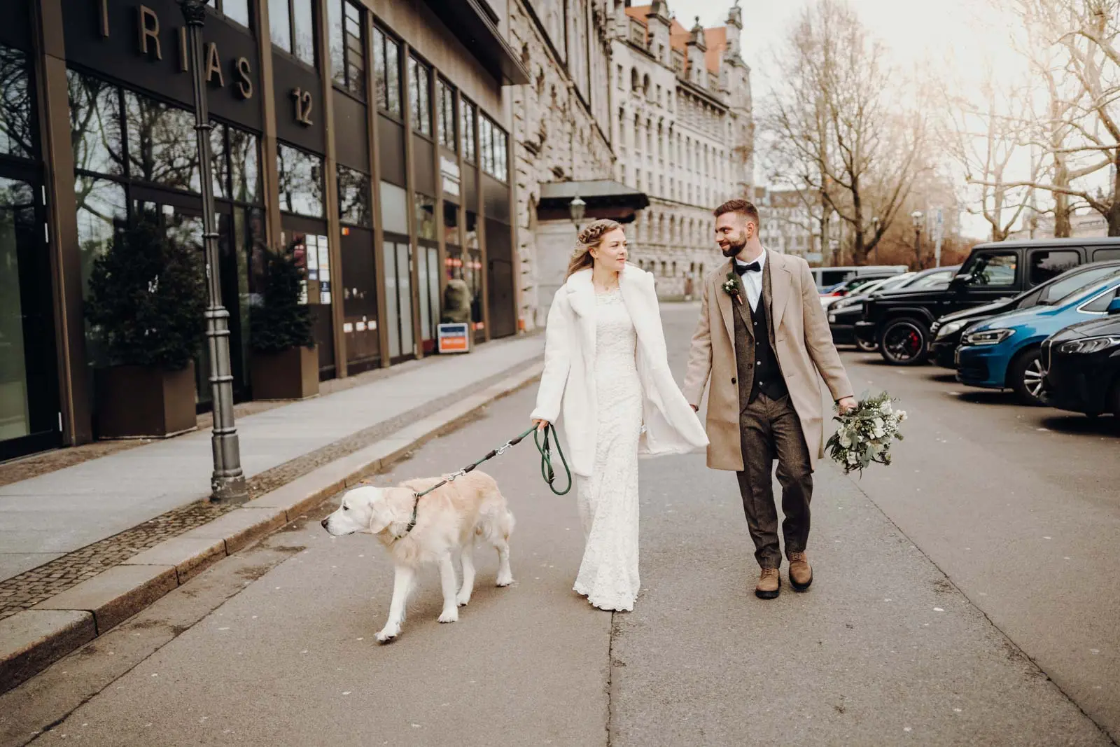 Brautpaar und Hund spazieren durch die Innenstadt Leipzig Brautpaar laeuft Hand in Hand mit ihrem Golden Retriever durch die Innenstadt Leipzig, im Hintergrund historische Gebaeude. Hochzeit Ratsplenarsaal Leipzig