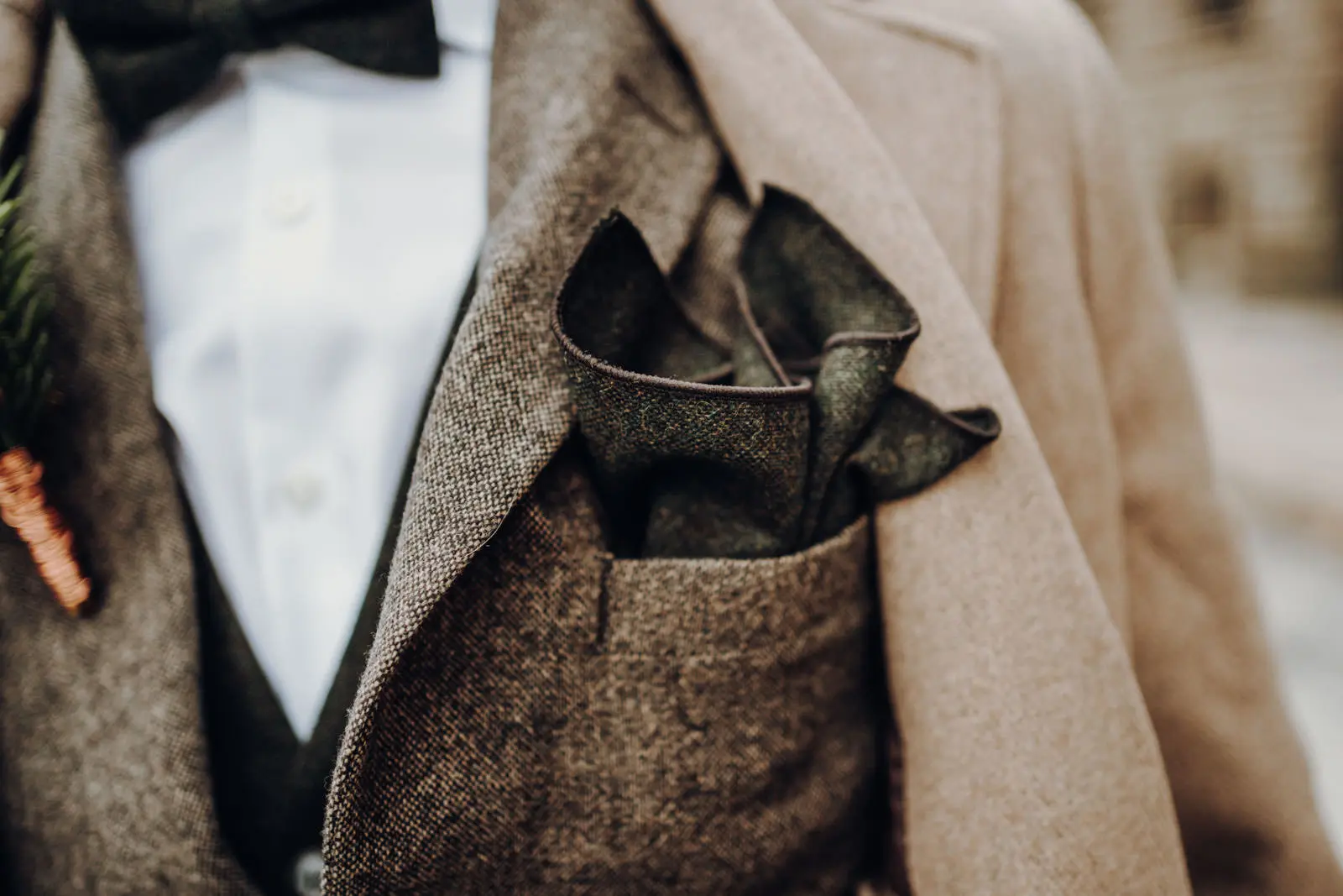 Einstecktuch Braeutigam – Detail Anzug Nahaufnahme des gefalteten Einstecktuchs in der Brusttasche des Braeutigams mit Boutonniere.