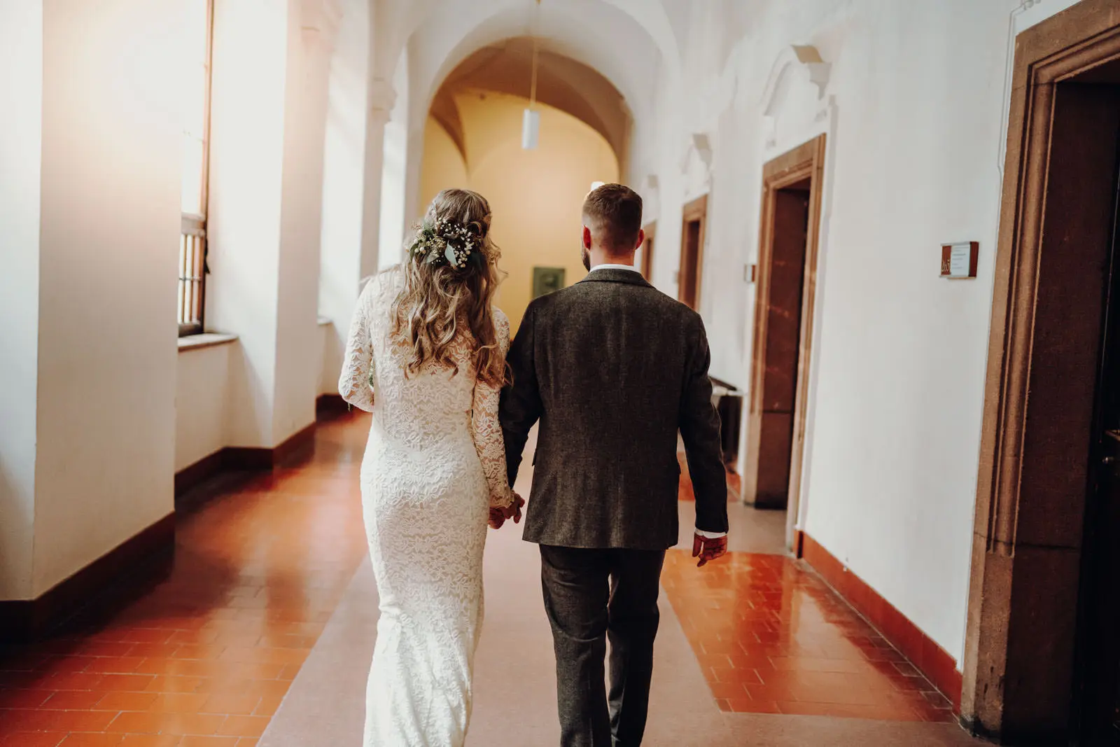 Brautpaar im Flur des Neuen Rathauses Leipzig Brautpaar laeuft Hand in Hand durch einen gewoelbten Flur des Neuen Rathauses Leipzig mit Terrakottaboden. Hochzeit Ratsplenarsaal Leipzig